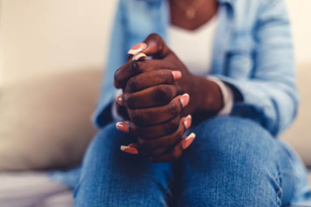 Cropped shot of an unrecognisable woman sitting alone and feeling anxious during her consultation. Closeup hands of anxious patient in therapy. Zoom in on hands of nervous person. Hands clasped, depressed person in psychotherapy. dark hollow